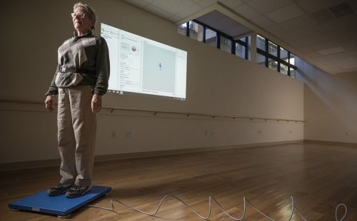 A research subject at the Marcus Institute for Aging Research stands on a measuring platform with a computer read-out reflected on the wall behind.
